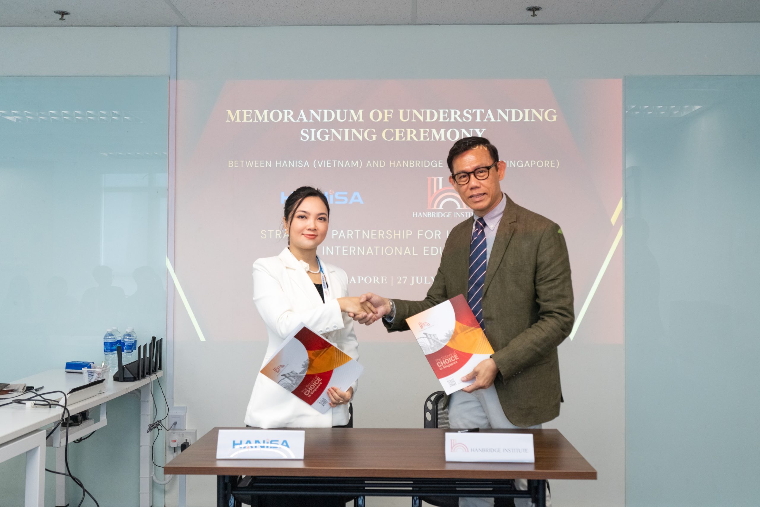 Dr Alan Go from Hanbridge Institute and Ms. Le An Na from HANISA shaking hands after signing the Singapore–Vietnam education partnership agreement.