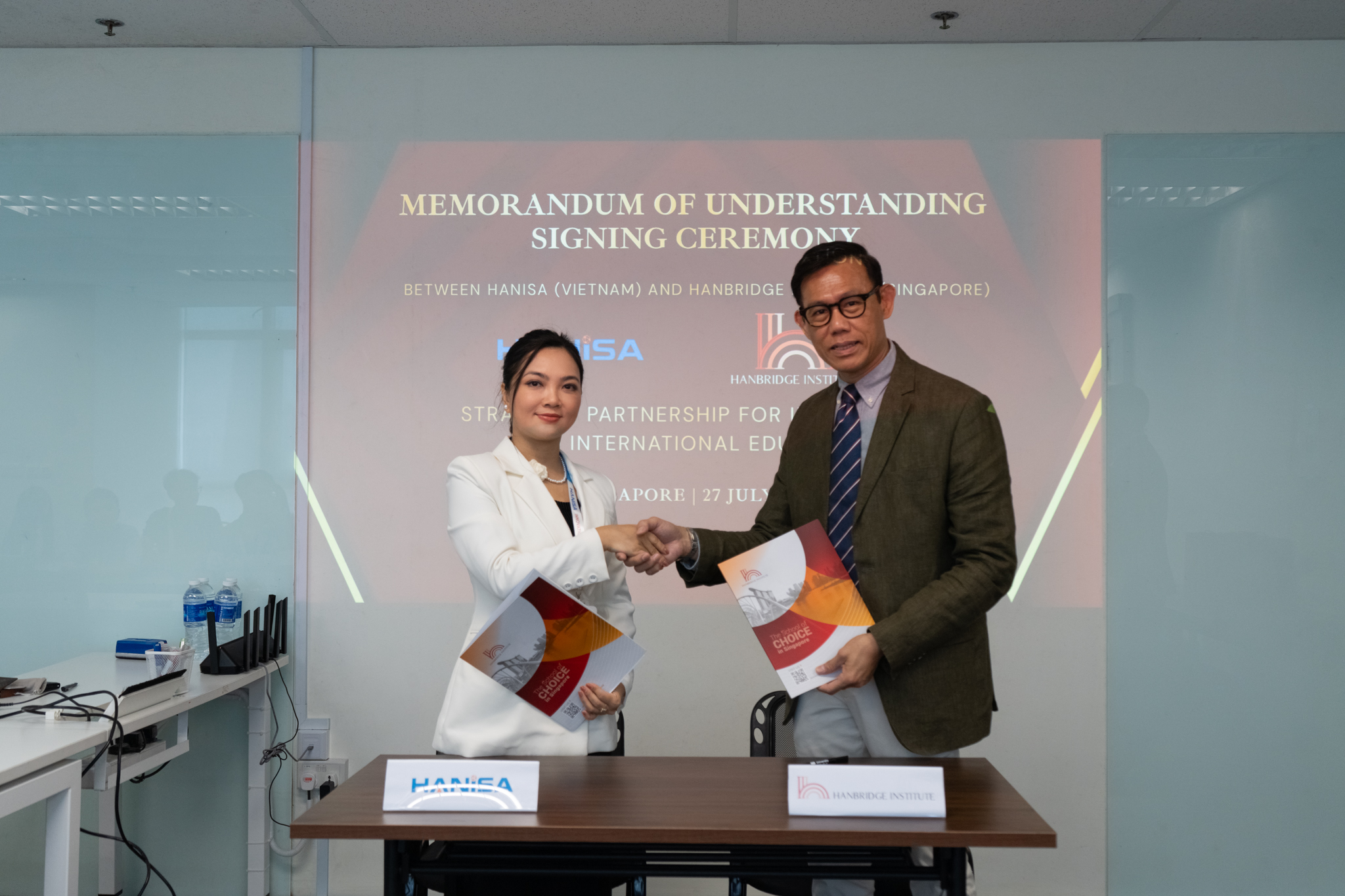 Dr Alan Go from Hanbridge Institute and Ms. Le An Na from HANISA shaking hands after signing the Singapore–Vietnam education partnership agreement.